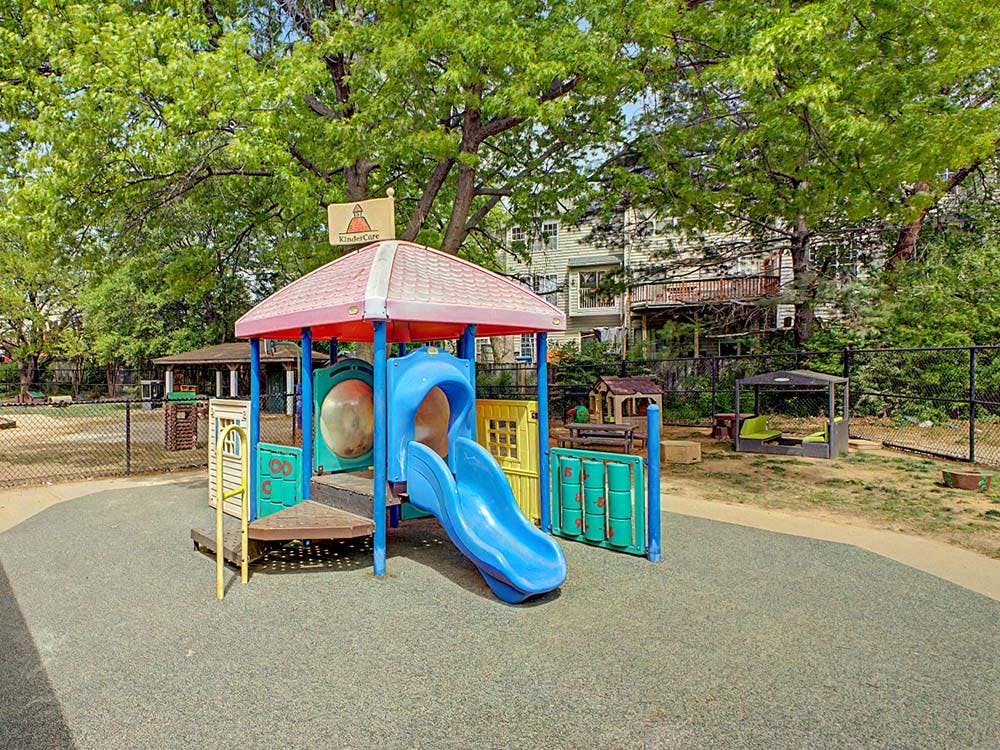 A colorful playground set with a blue slide on a rubberized surface
