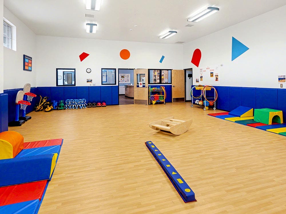 Indoor playroom with soft play equipment, small basketball hoops, and toys