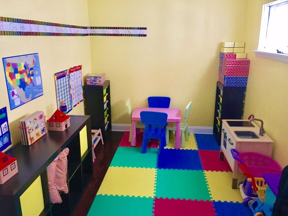 Children's play area with colorful floor mats, small table, and toy kitchen