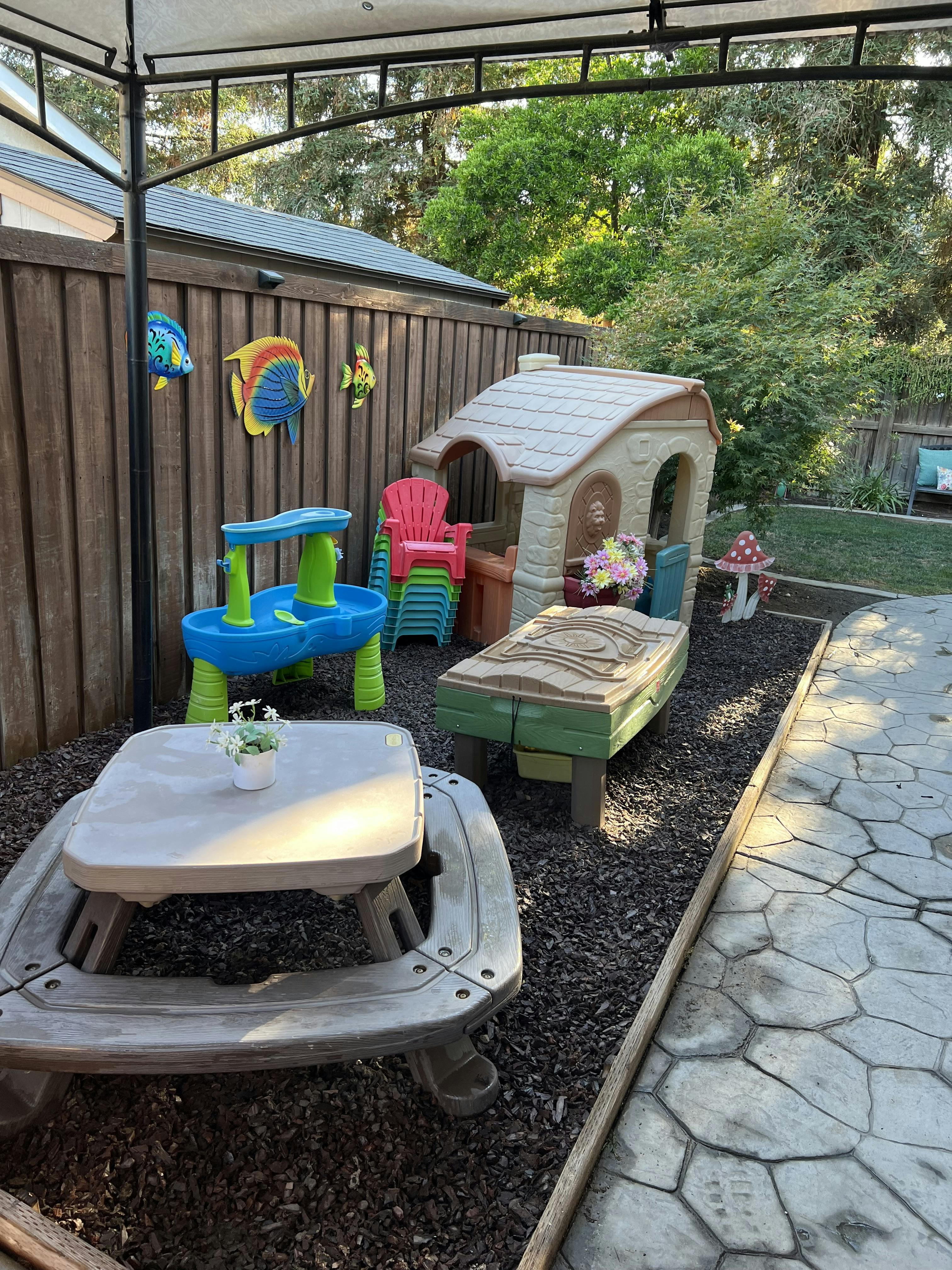 Outdoor play area with a playhouse, water table, and picnic table