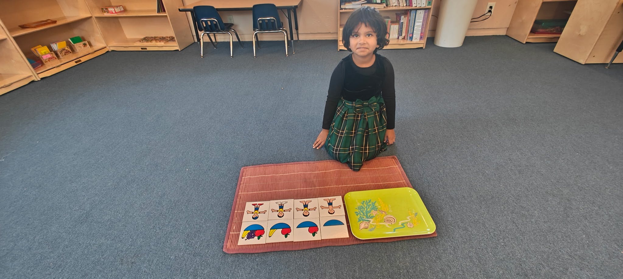 Child kneeling on floor with puzzle in a classroom