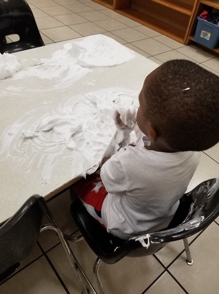 Child playing with shaving cream on a table