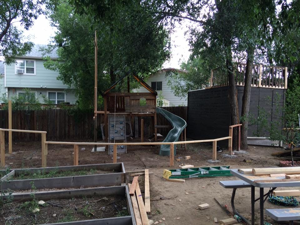 Backyard with a wooden play structure, slide, and raised garden beds