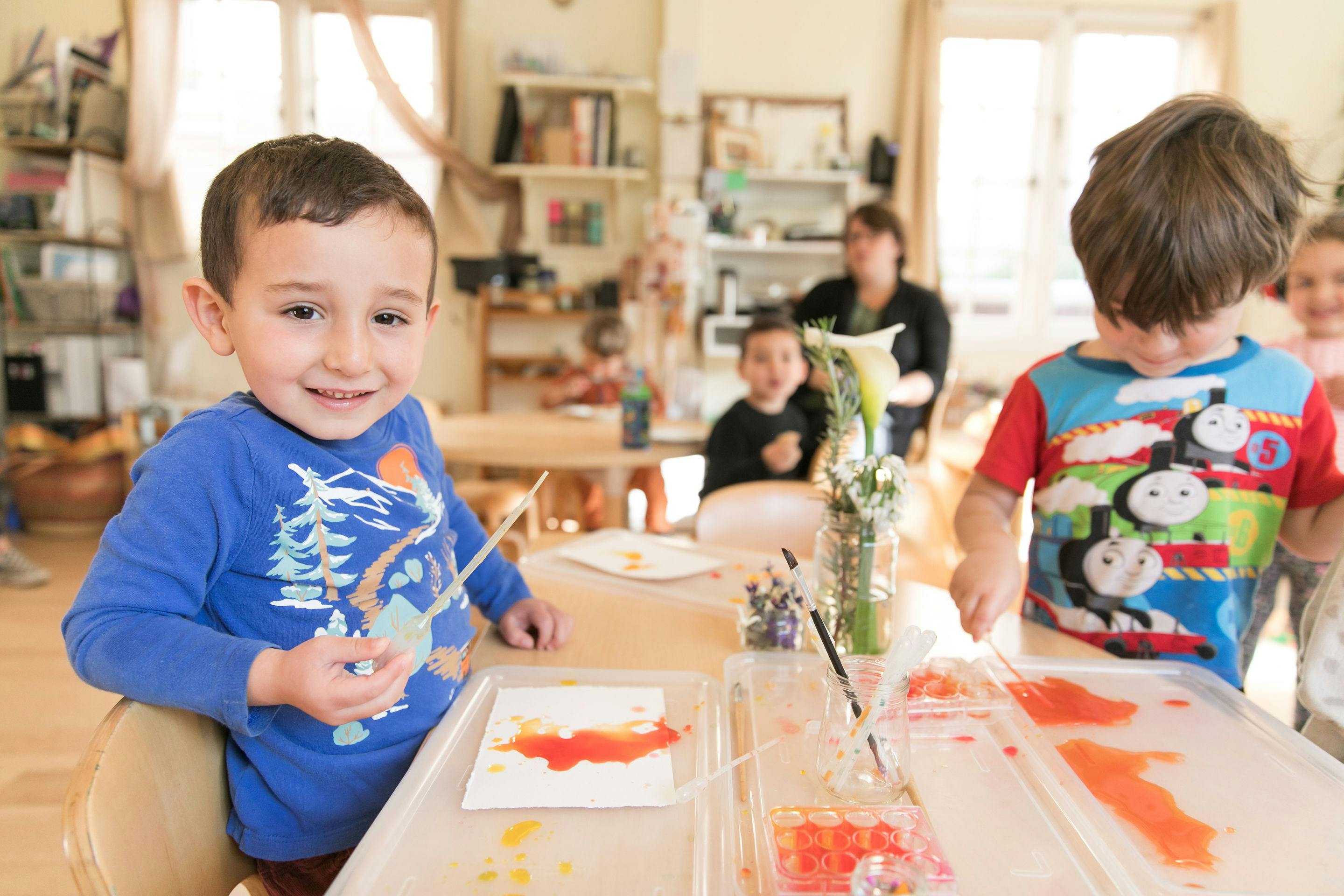 Child painting at a table in a classroom