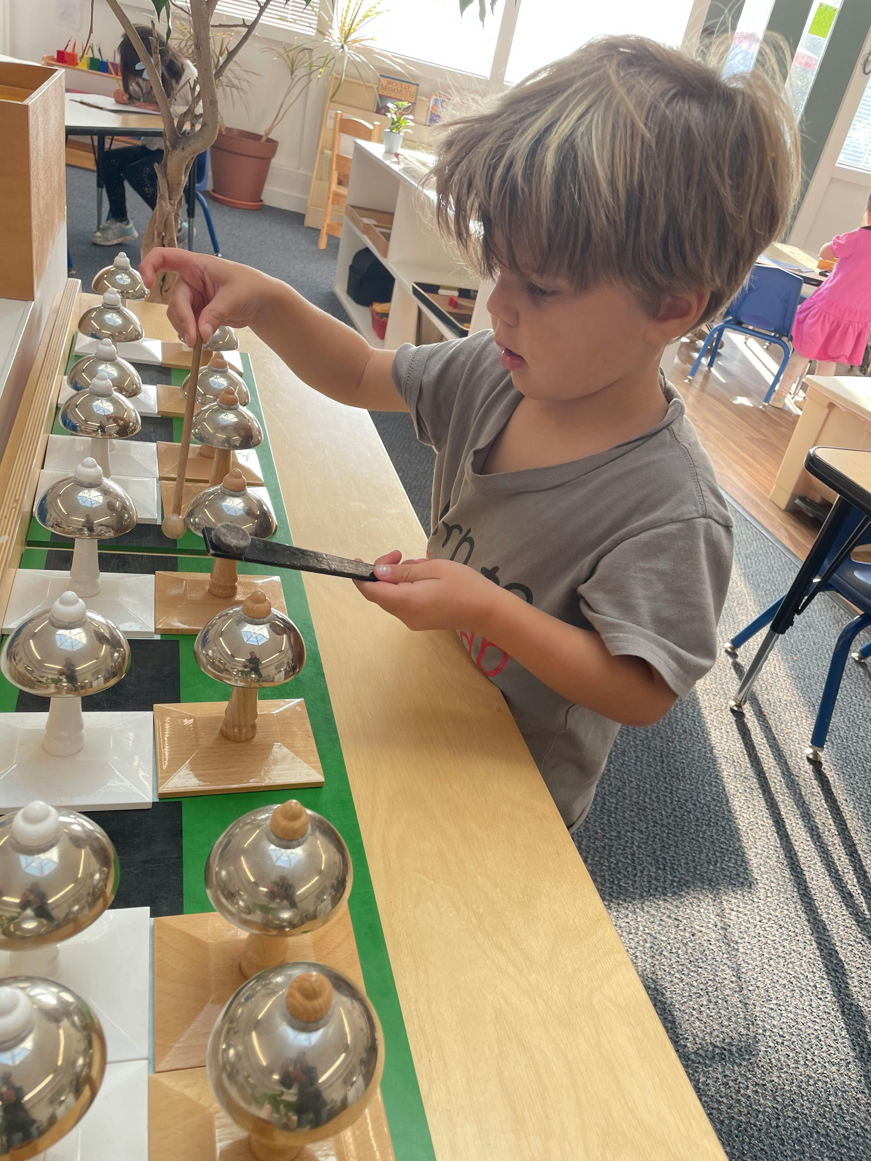 Child playing musical hand bells in a classroom