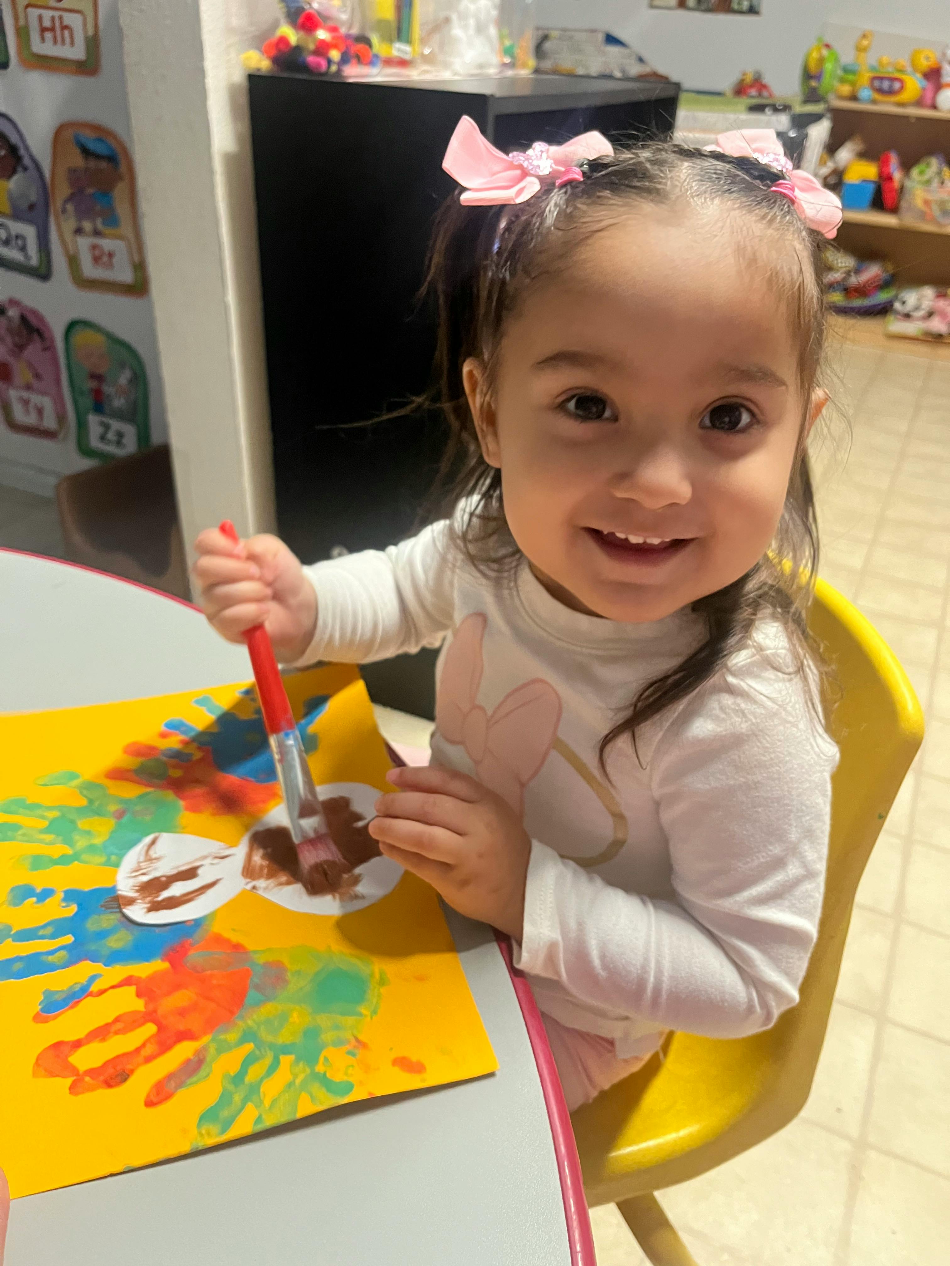 Child painting on paper with handprints