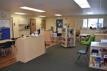 Empty classroom with tables, chairs, and shelves