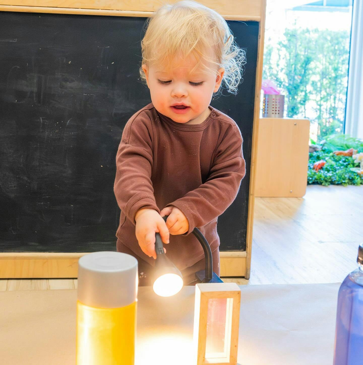 Child holding a lamp over a table with other glowing objects
