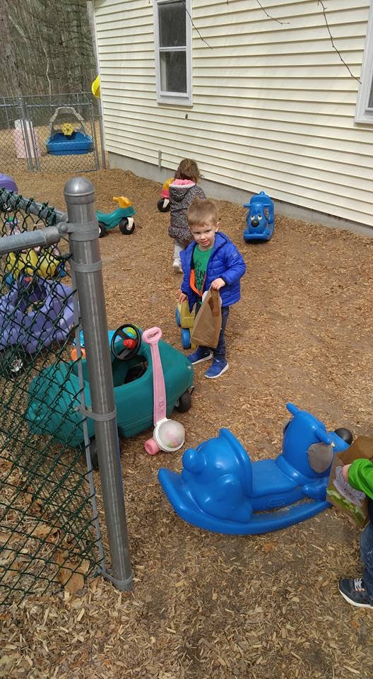 Child holding a paper bag on a playground with other children and toys