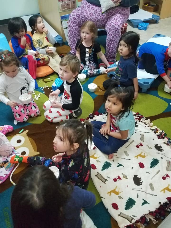 Children sitting on a colorful rug in a classroom