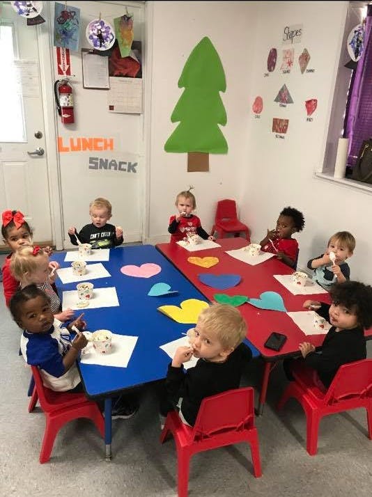 Children sitting at tables eating snacks in a classroom eating snacks