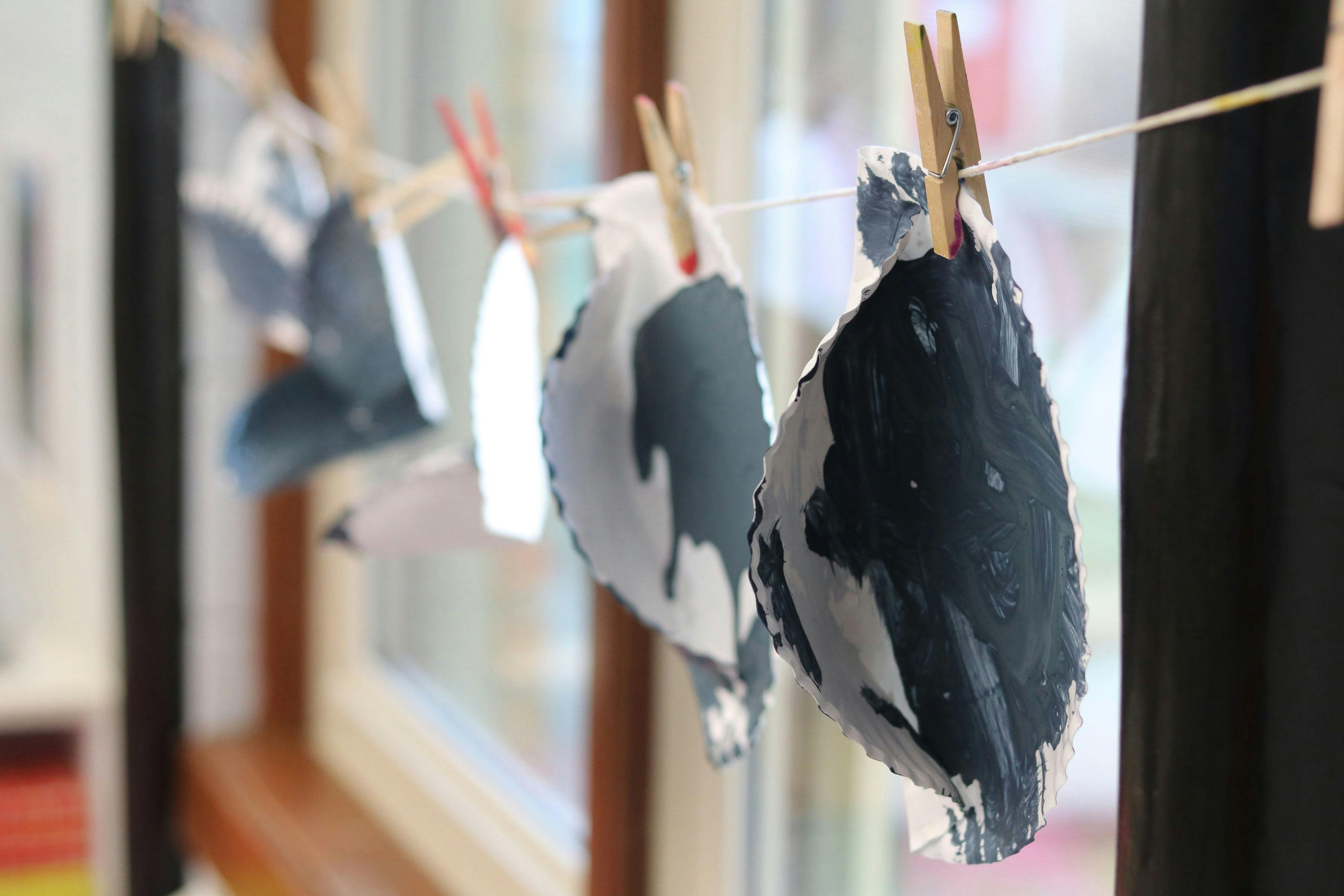 Paper cutouts with paint hanging on a string with clothespins