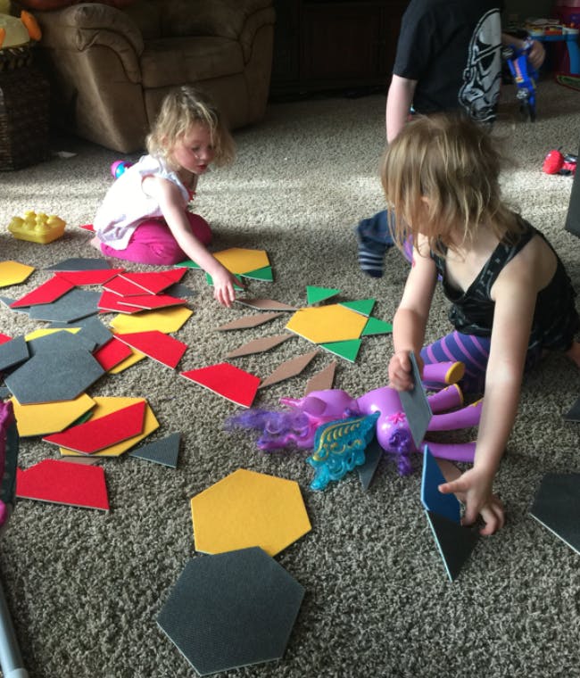 Two children playing with colorful geometric shapes on a carpet