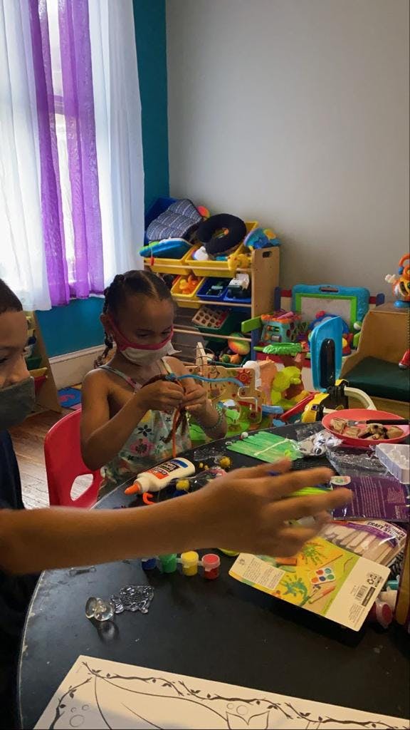 Child in mask doing crafts at a table