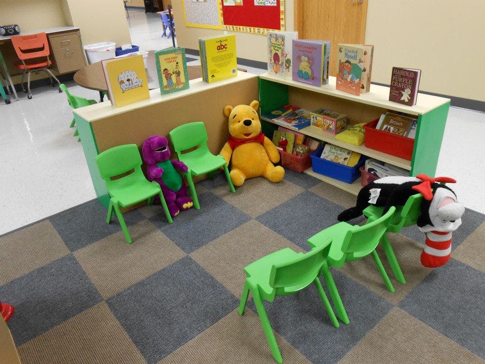 Stuffed animals sitting on chairs in a classroom