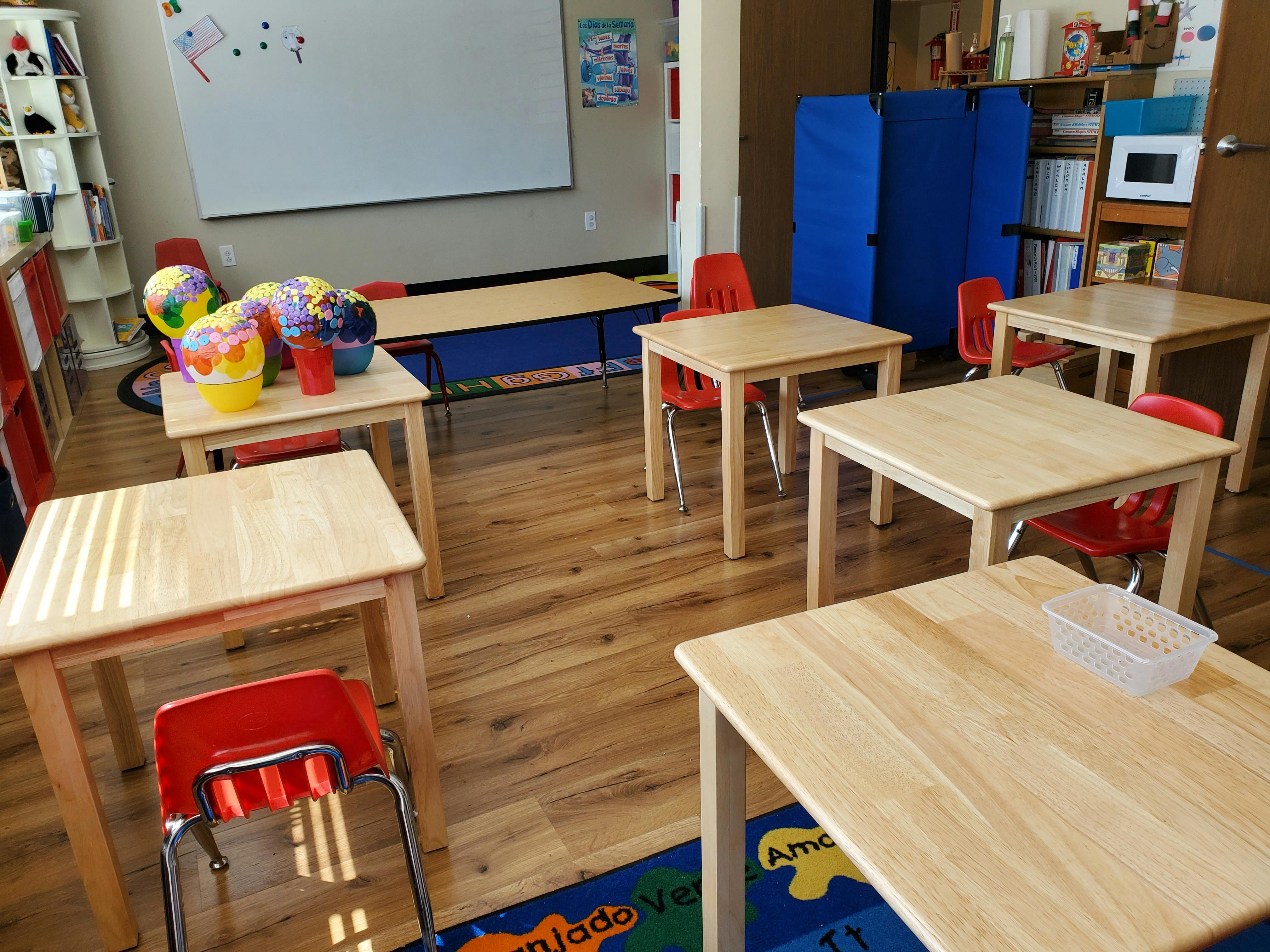 Classroom with small wooden tables and red chairs