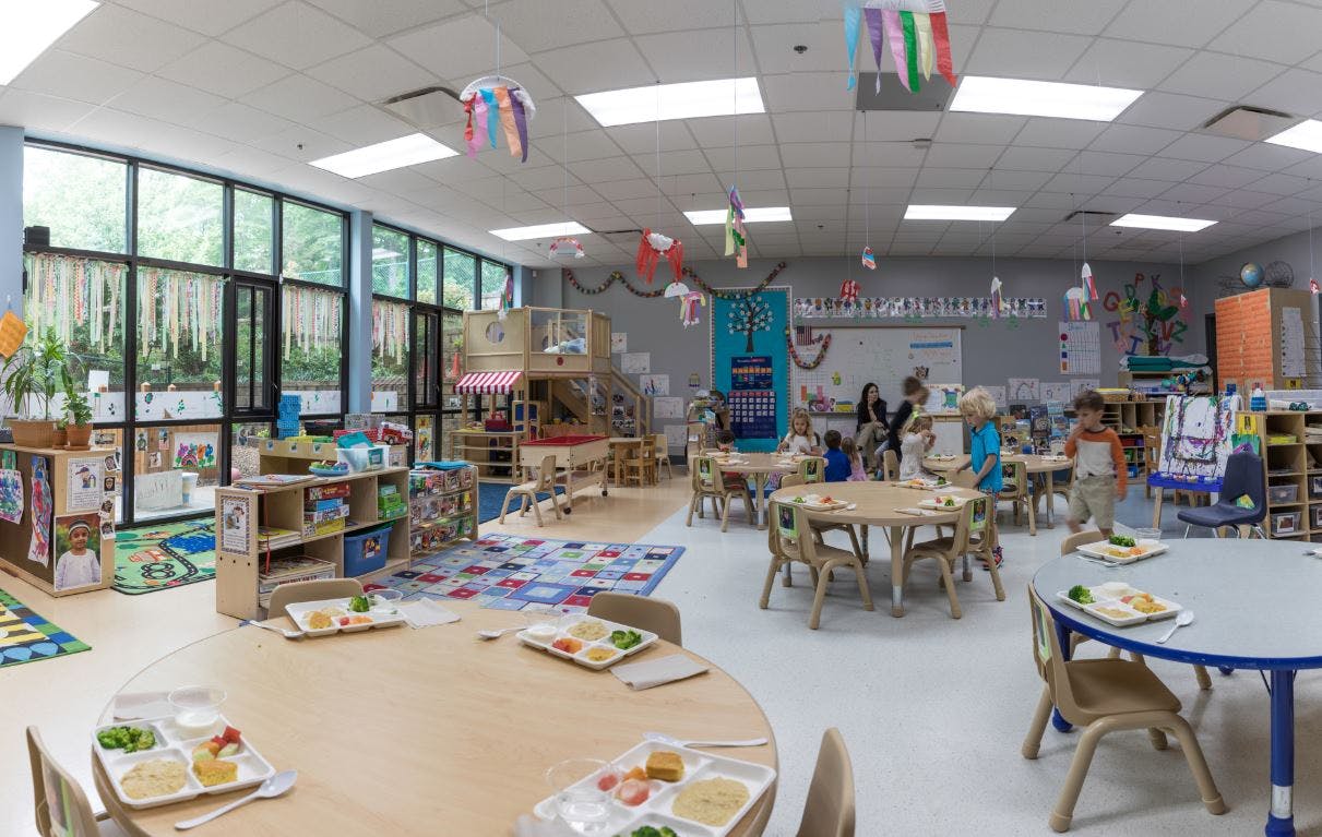 Classroom with tables set for meals and children in the background