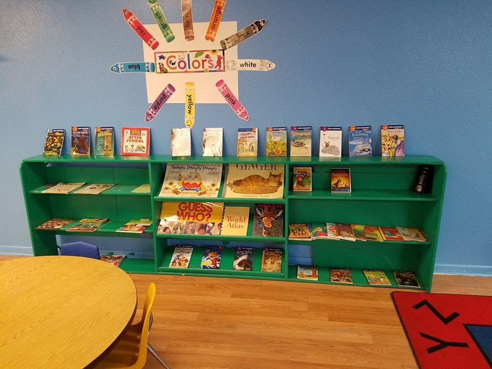 Green bookshelf with children's books and a "Colors" sign on the wall