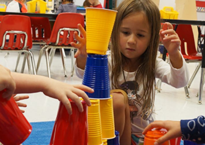 Child stacking colorful plastic cups in a classroom