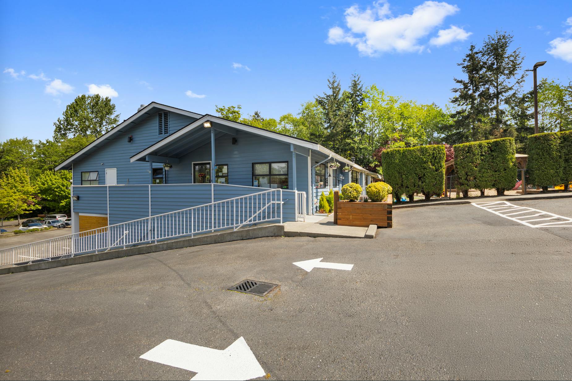 Exterior of a blue building with an accessibility ramp and a paved parking lot