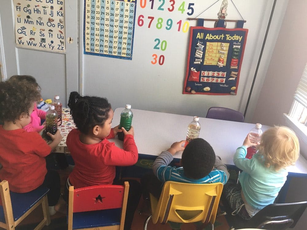 Children sitting at a table with bottles in a classroom