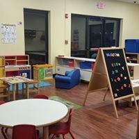 Classroom with small tables, chairs, and a chalkboard