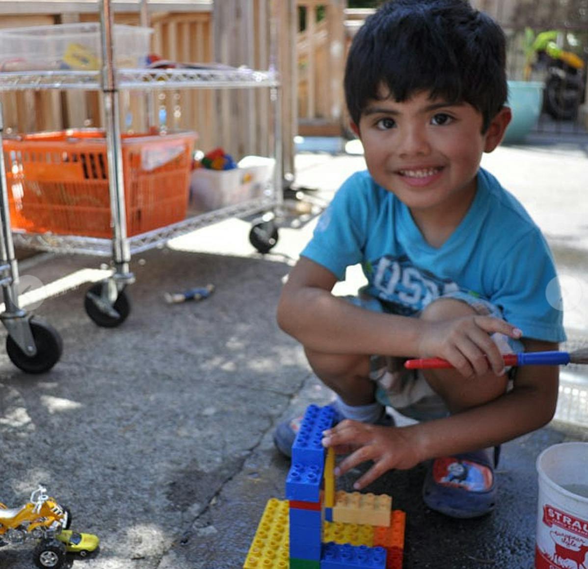Child crouching and building with colorful blocks