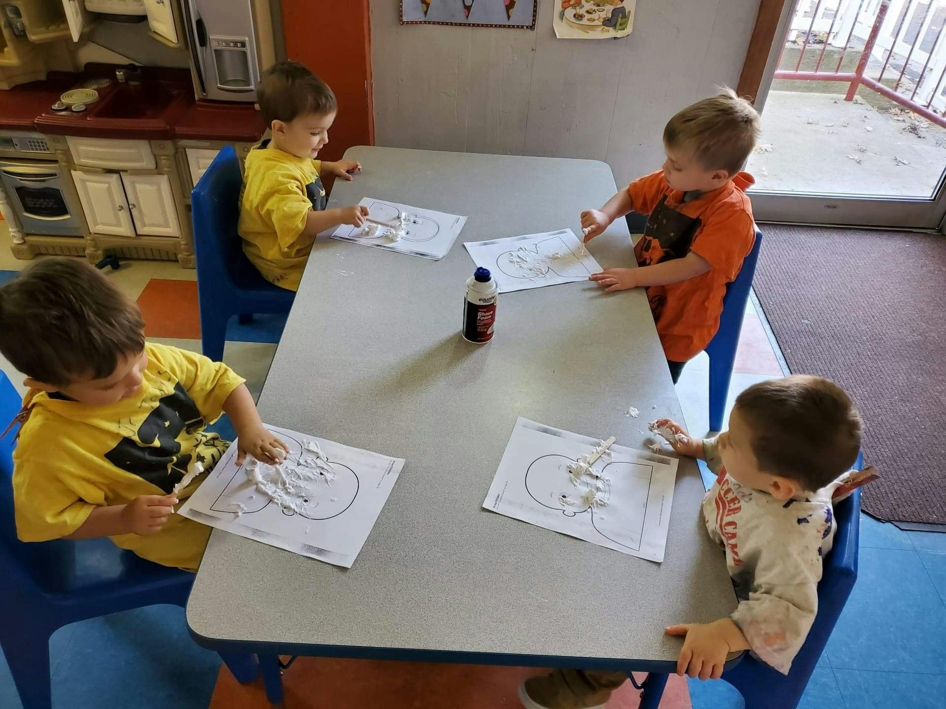 Four children sitting at a table doing crafts in-class art activities