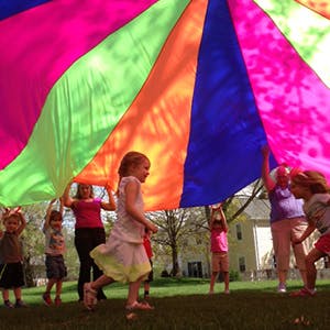 Children and adults playing with a colorful parachute outdoors