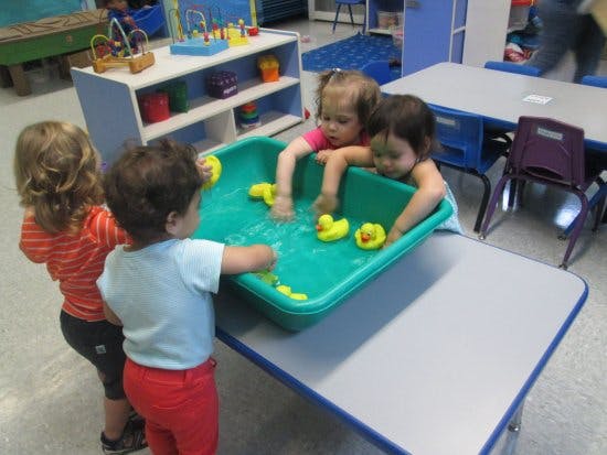 Children playing with rubber ducks in a water table