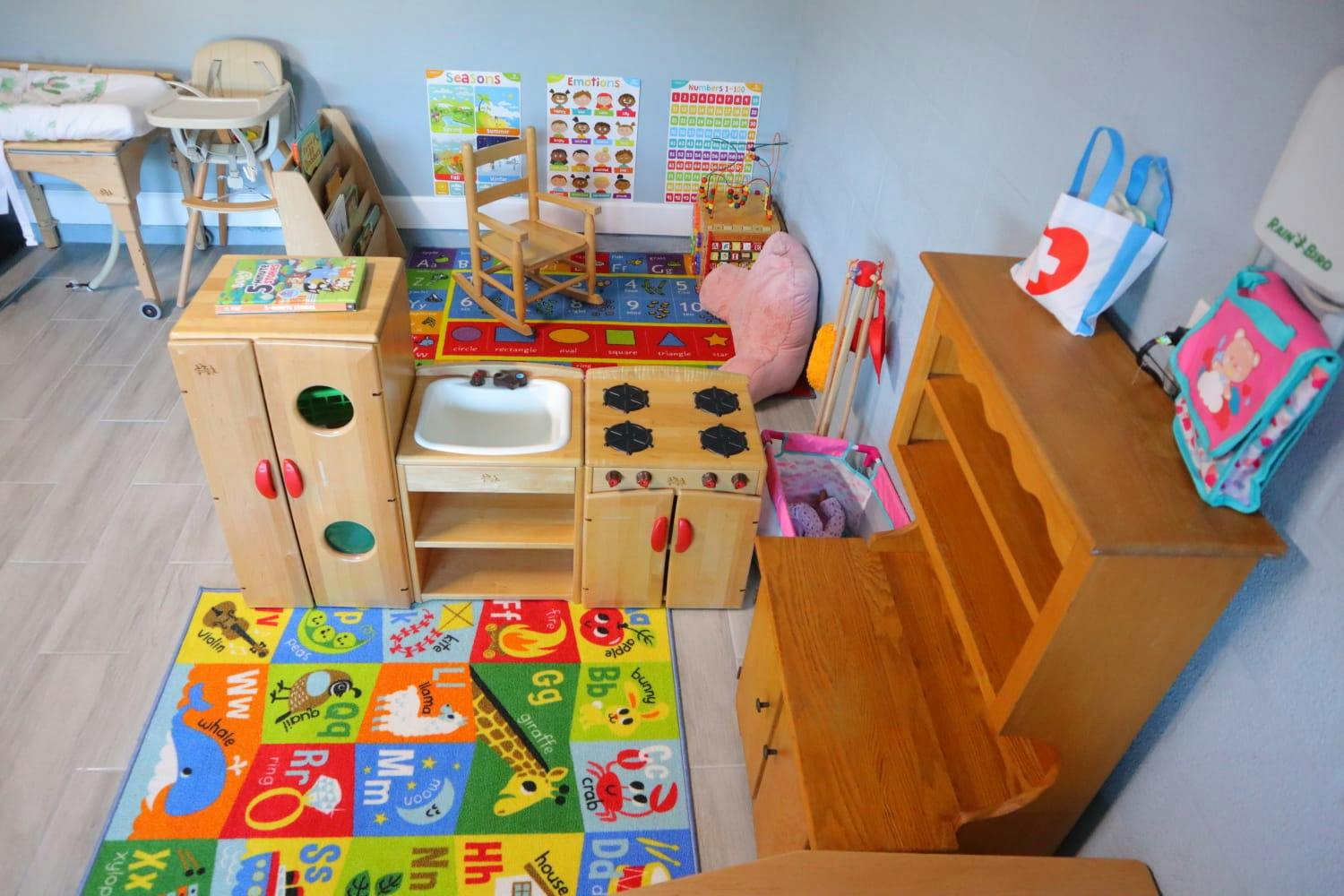 Playroom with toy kitchen, colorful rug, and small chairs