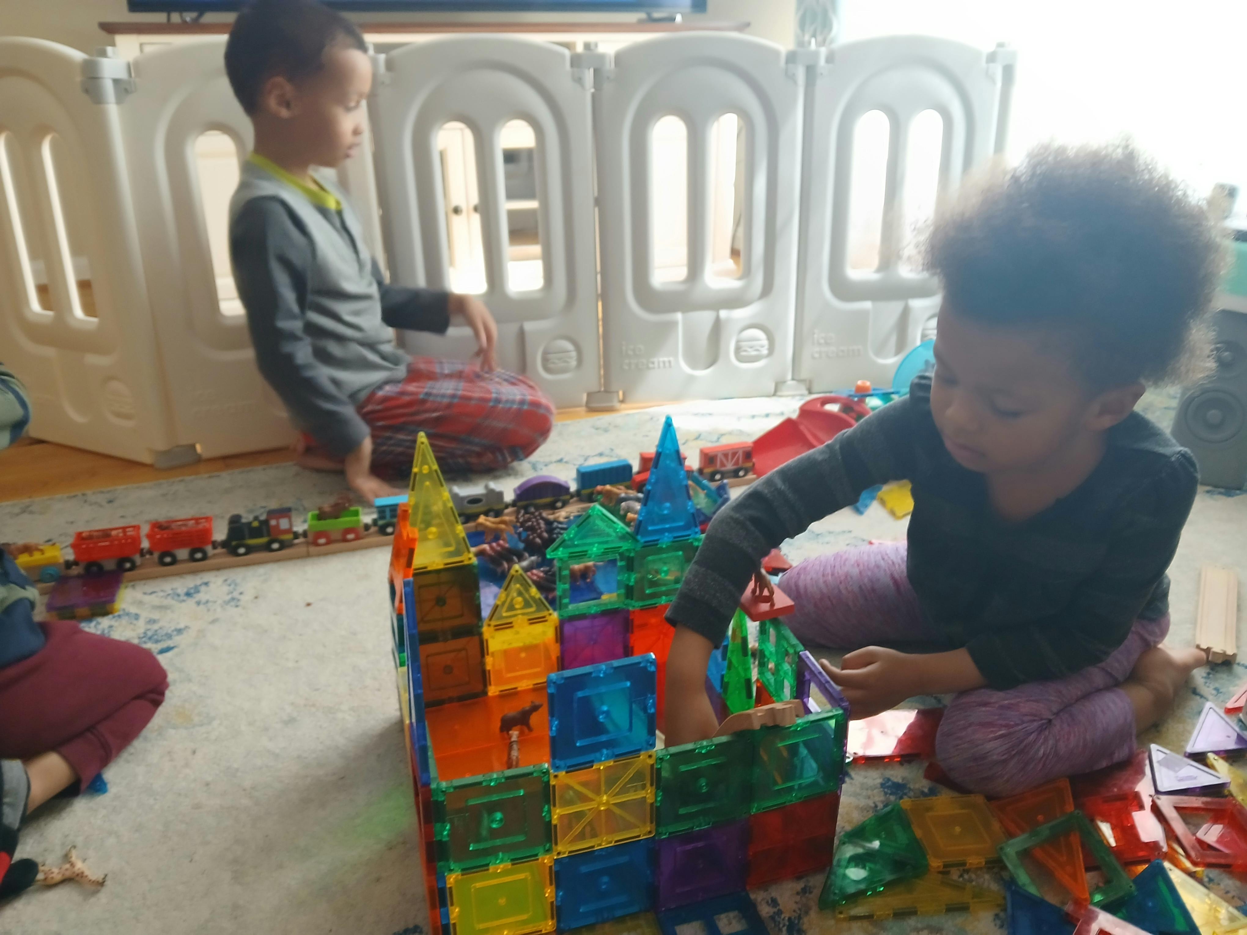 Two children playing with magnetic building blocks and a toy train