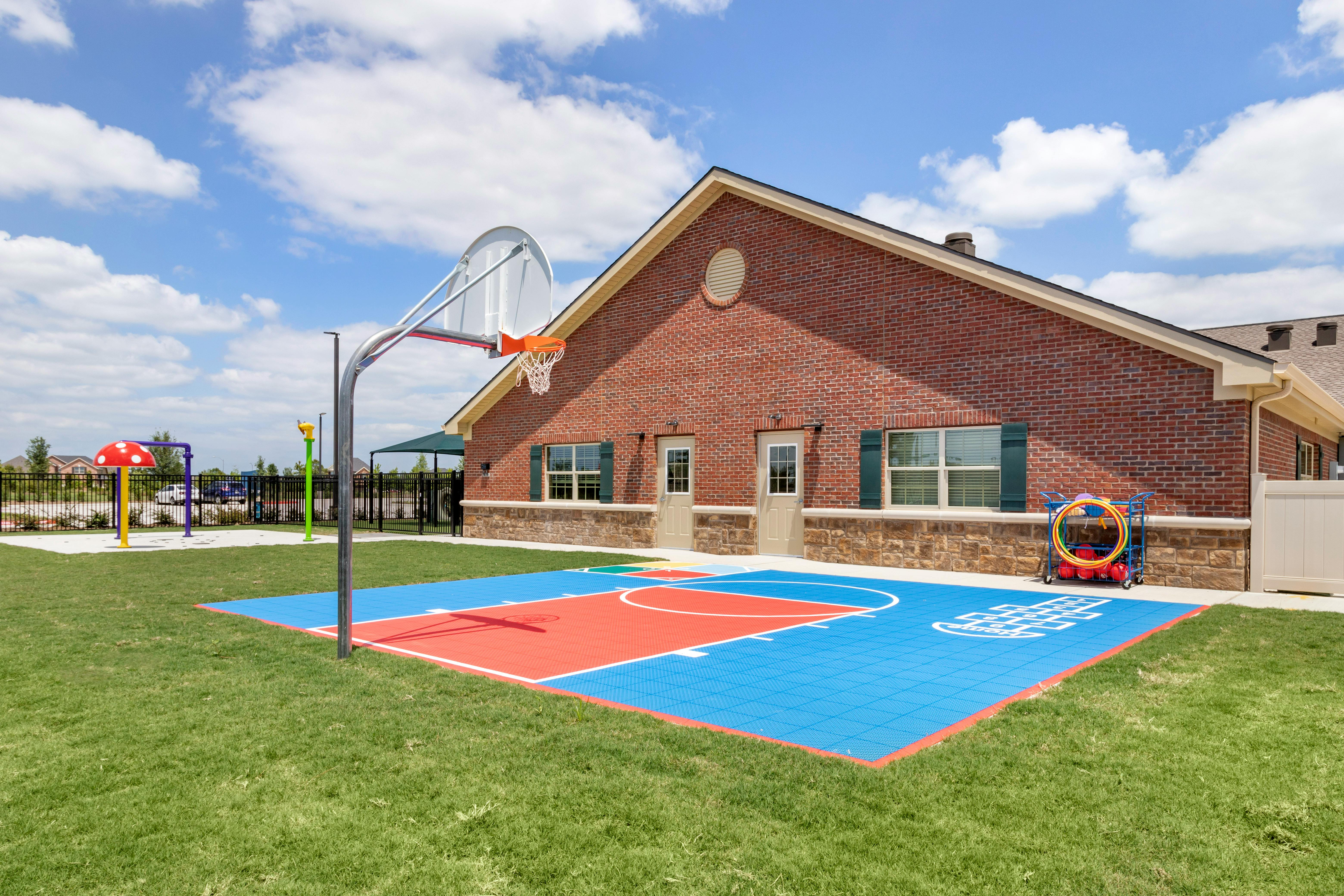 Basketball court with red and blue sections next to a brick building