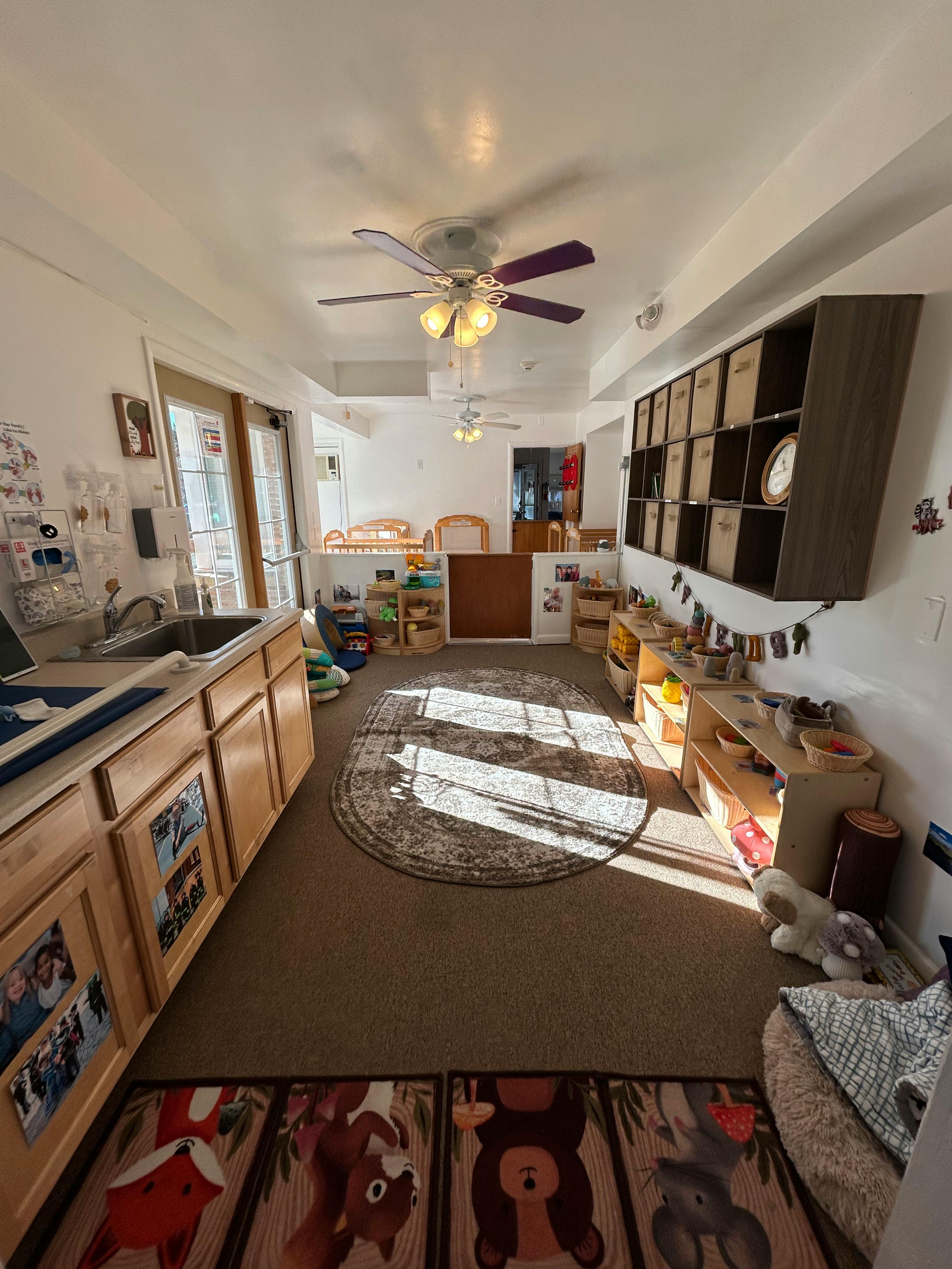 Classroom with a sink, cabinets, shelves, and a rug on a rug