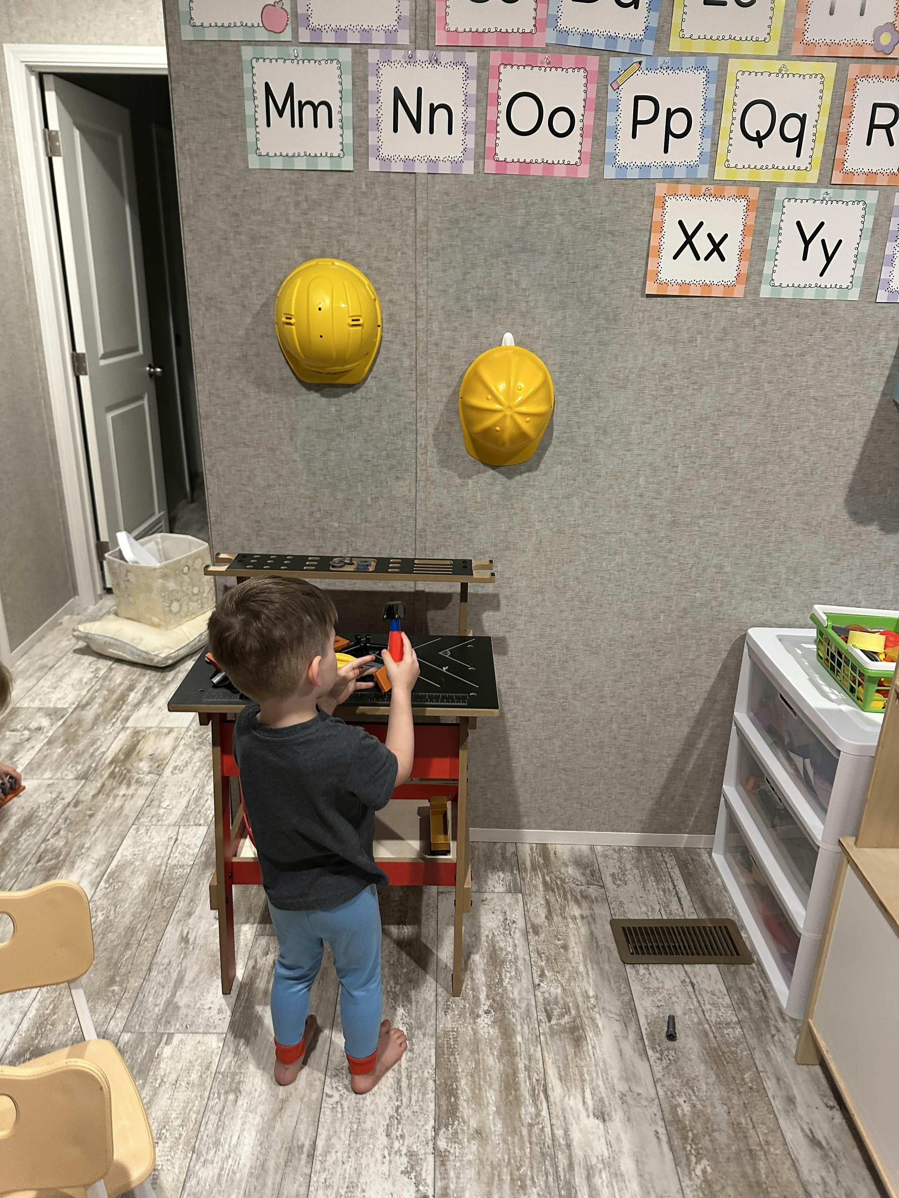 Child playing at a toy workbench in a classroom