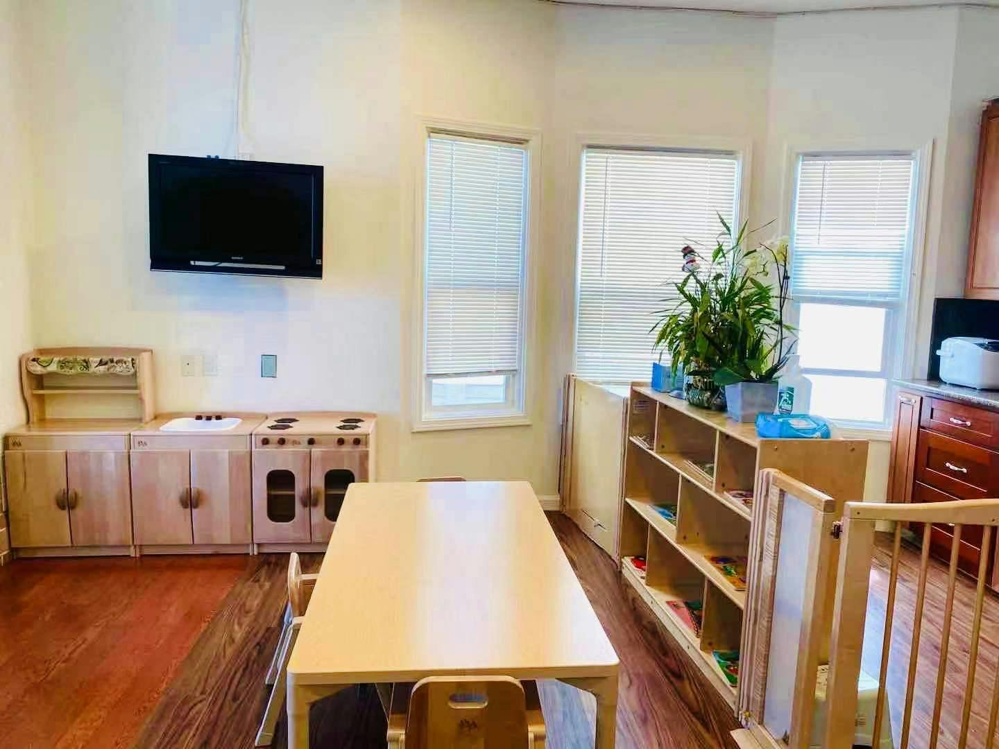 Classroom with a long table, chairs, shelves, and a play kitchen