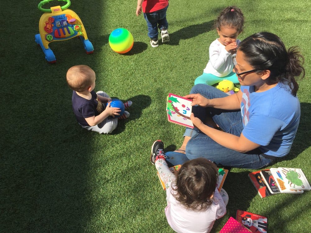 Person reading a book to children on grass