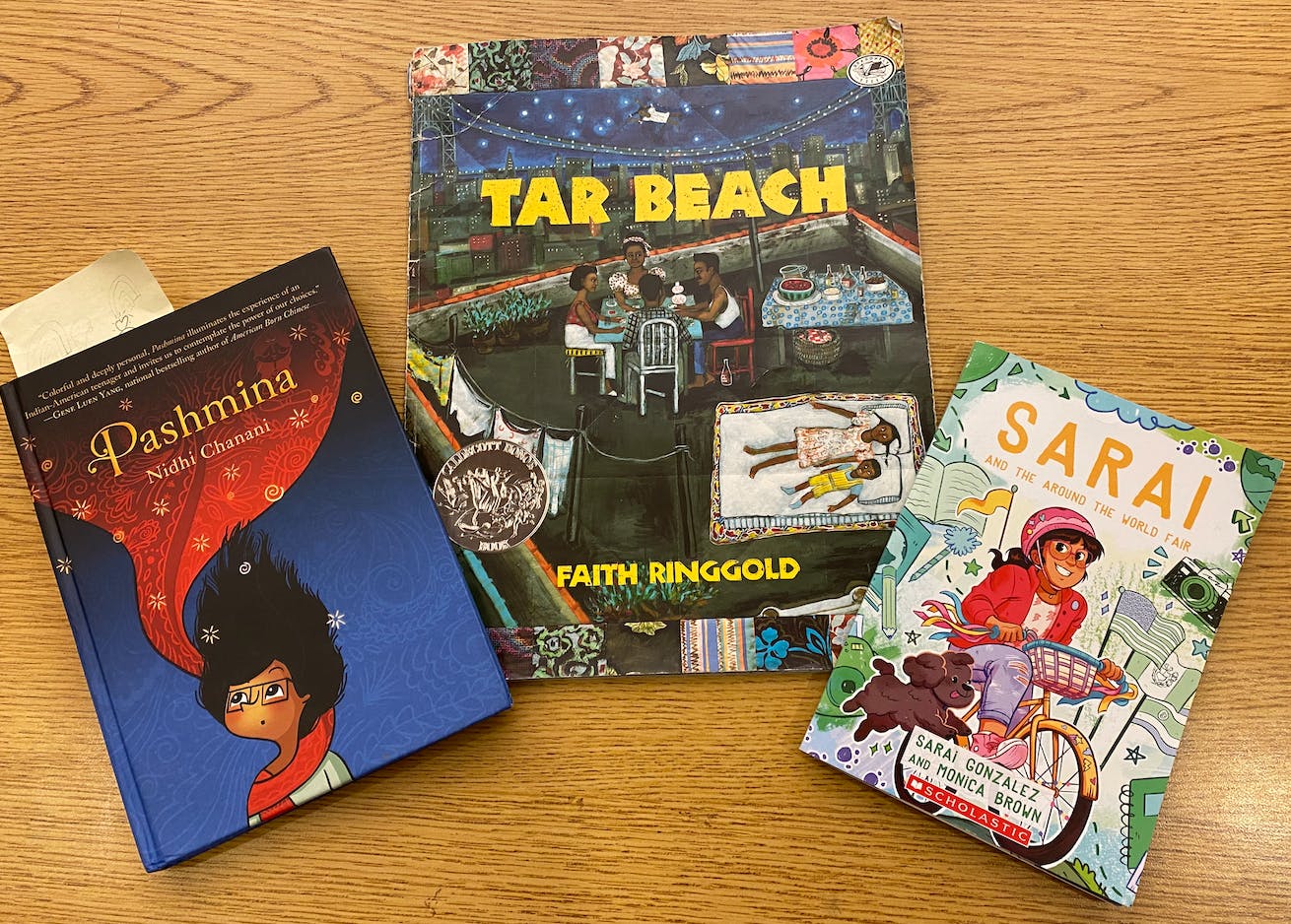 Three children's books arranged on a wooden table