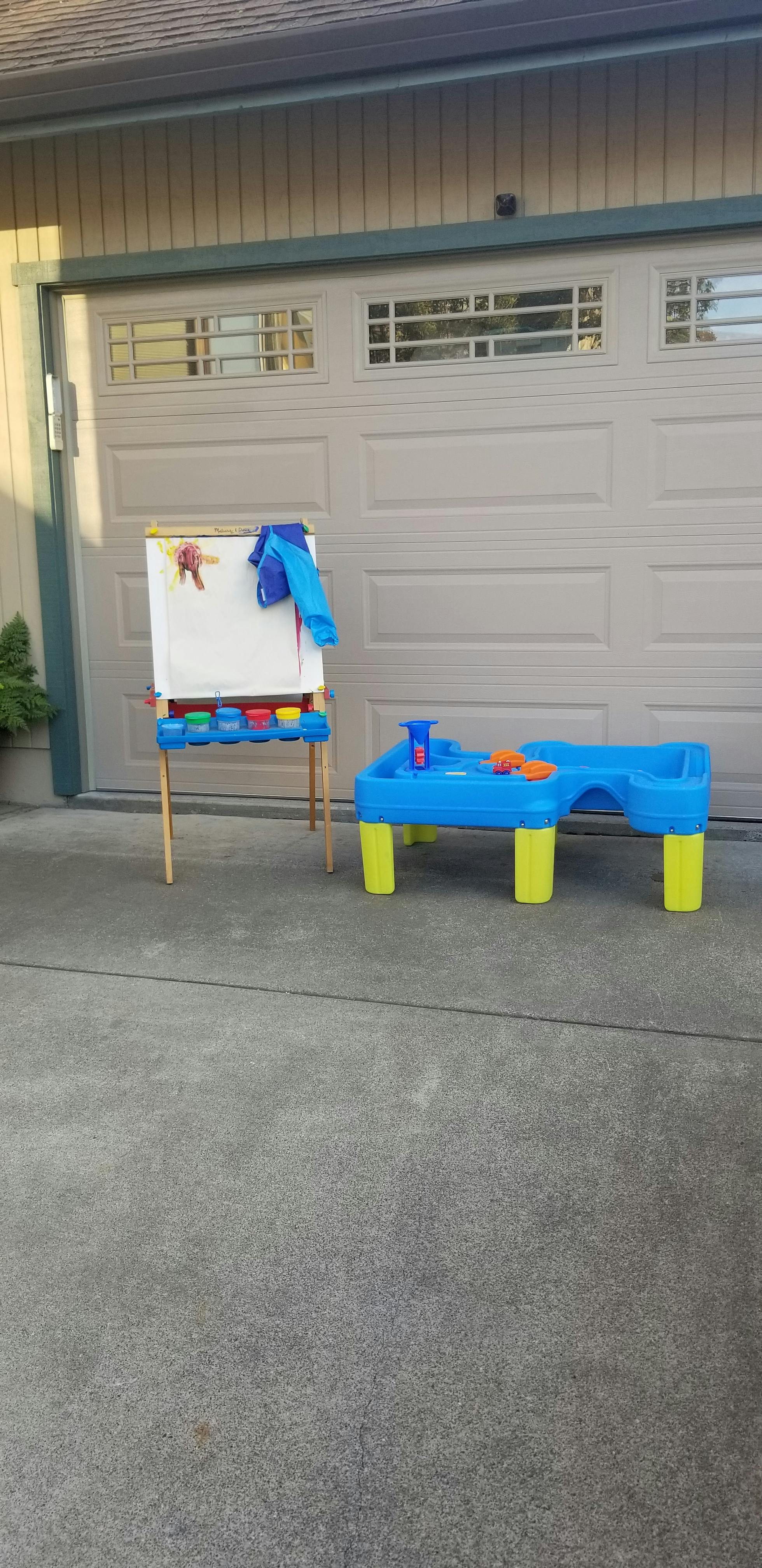 Child's easel with paint and a blue water table with toys