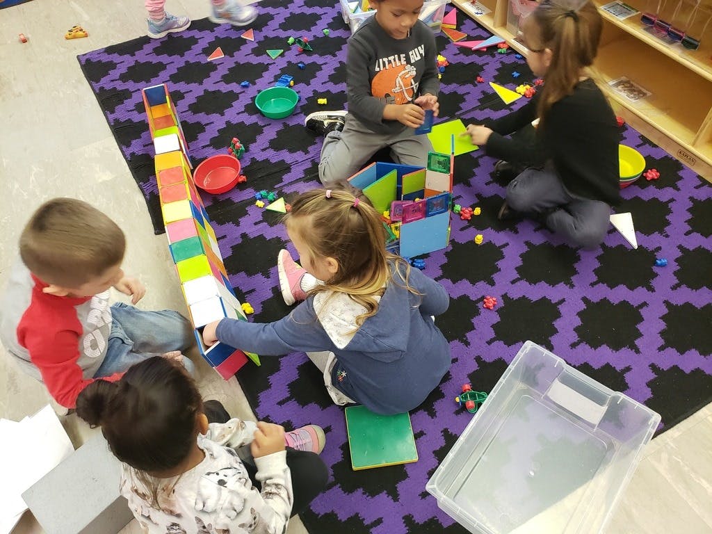 Children playing with blocks and toys on a purple rug