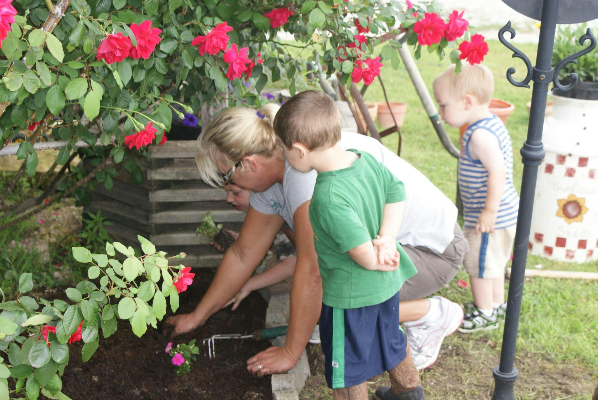 Person and two children planting in a garden