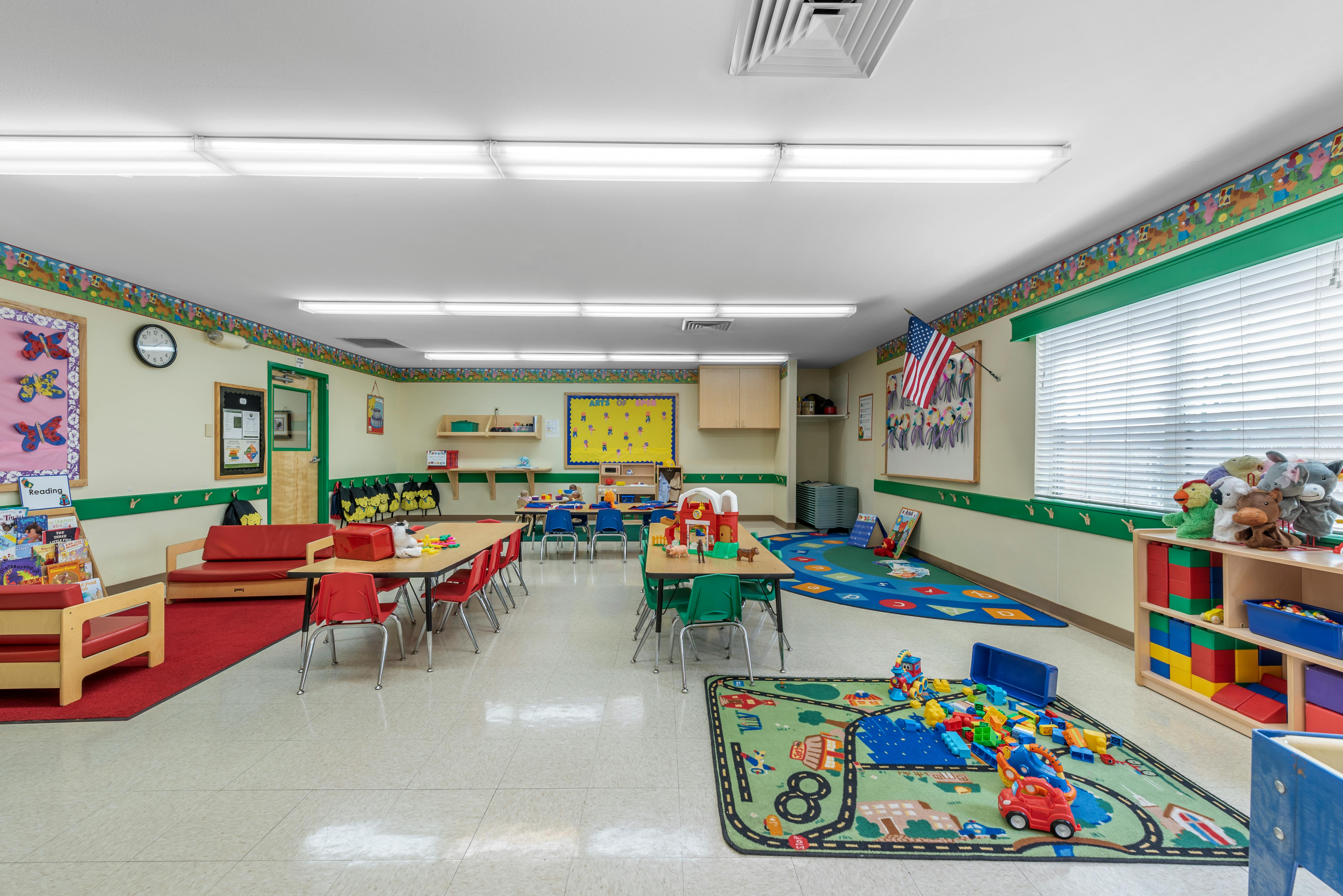 Colorful classroom with tables, chairs, toys, and American flag