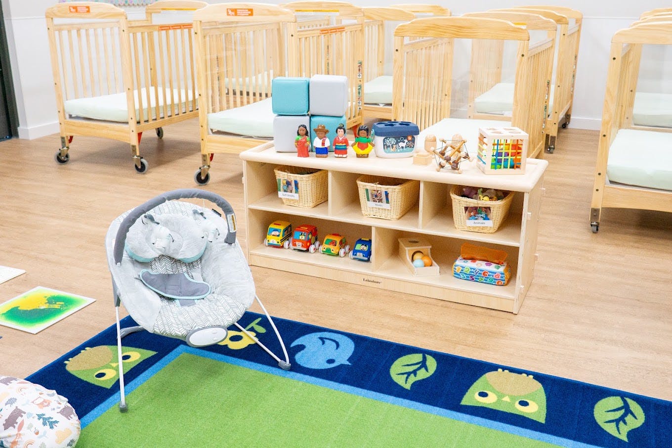 A baby bouncer and a wooden toy shelf in a childcare center