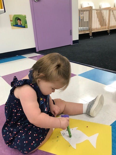 Child drawing on paper with a crayon
