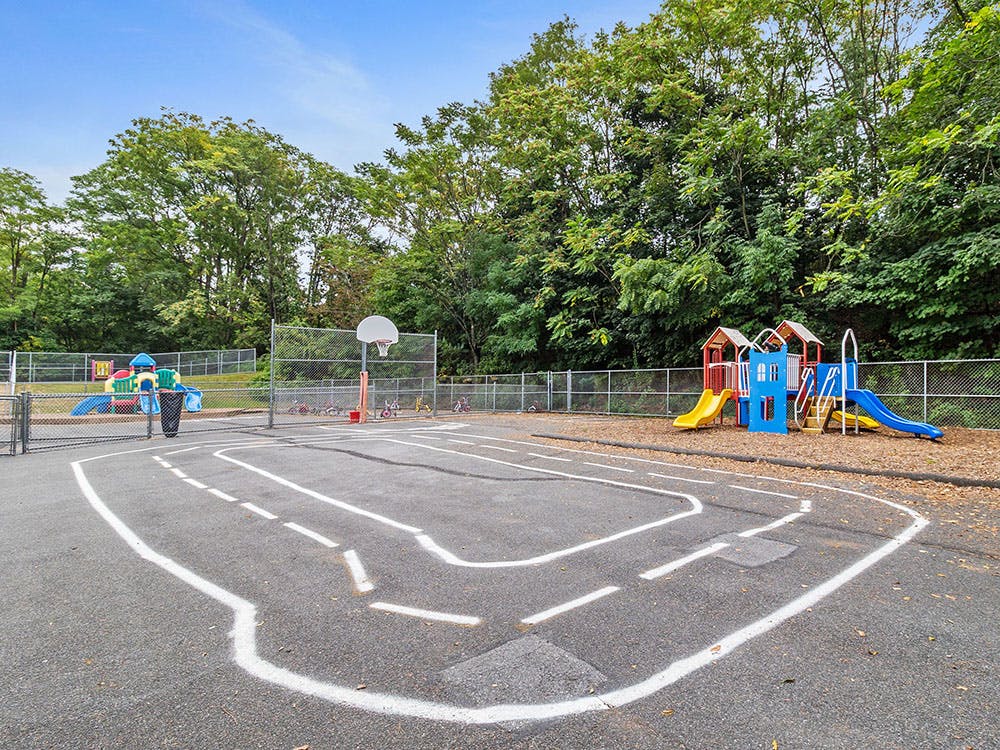 Outdoor playground area with toy road, basketball hoop, and colorful slides