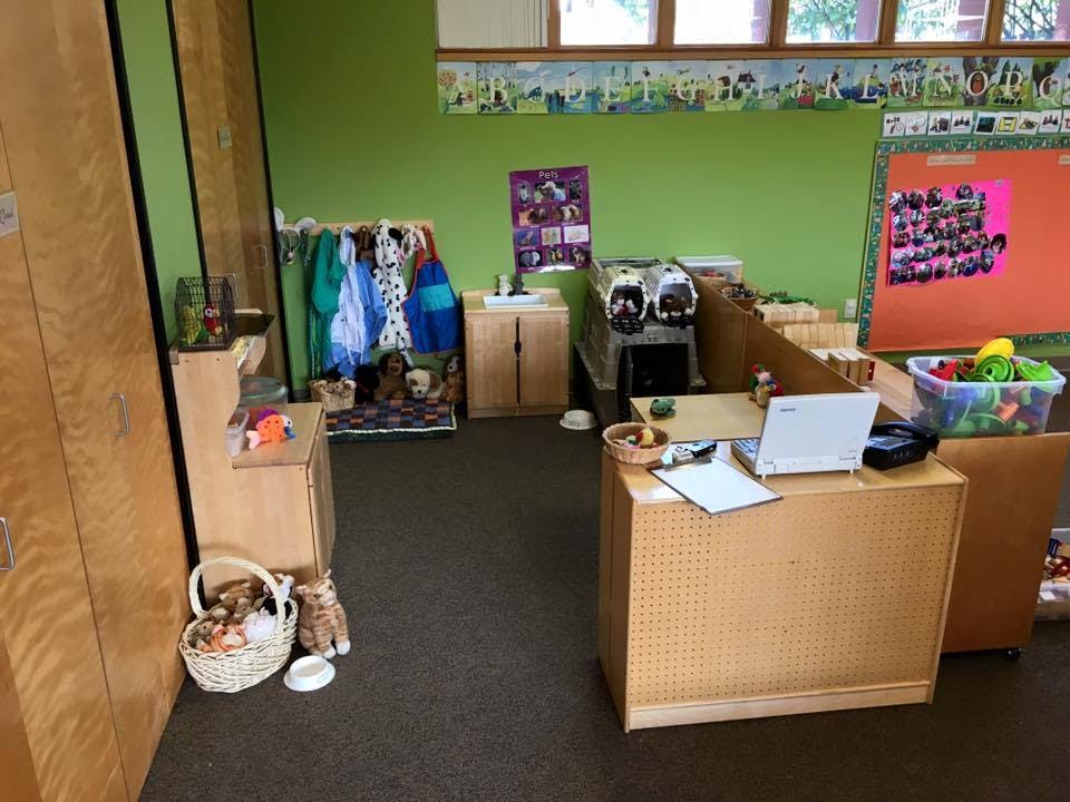 Classroom with green walls, coat rack, and a desk with a laptop