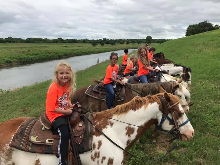 Children on horseback riding along a river