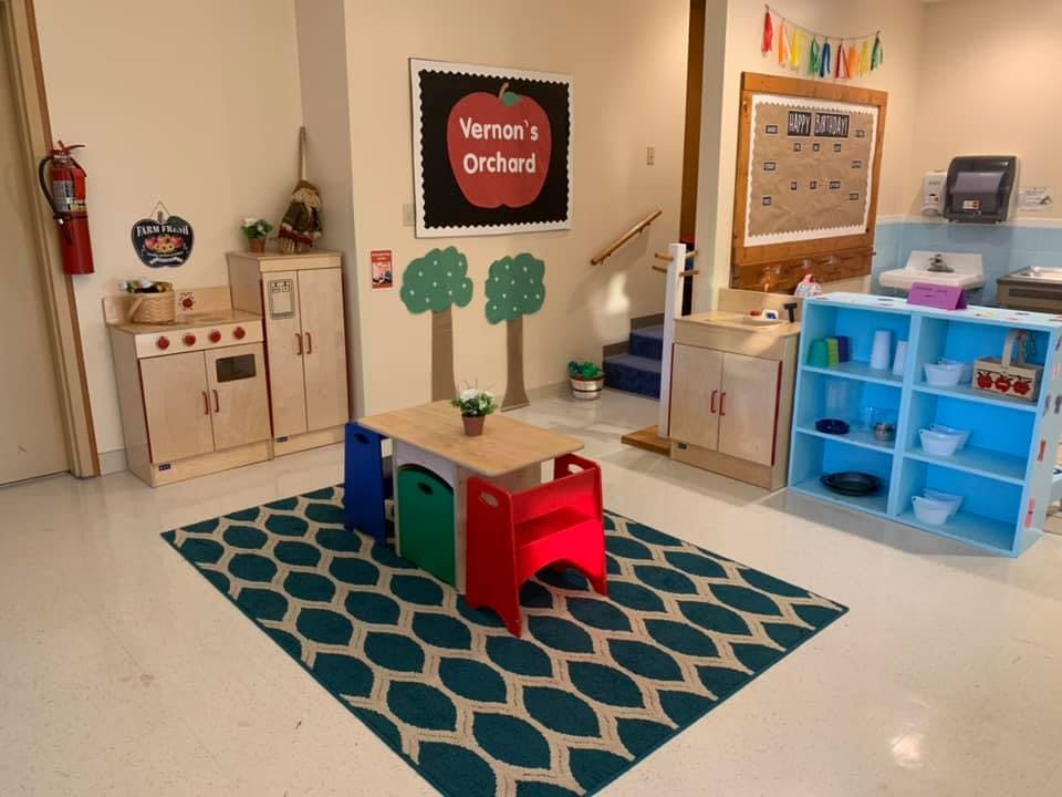 Playroom with small table and chairs, play kitchen, and blue shelving unit with white shelves