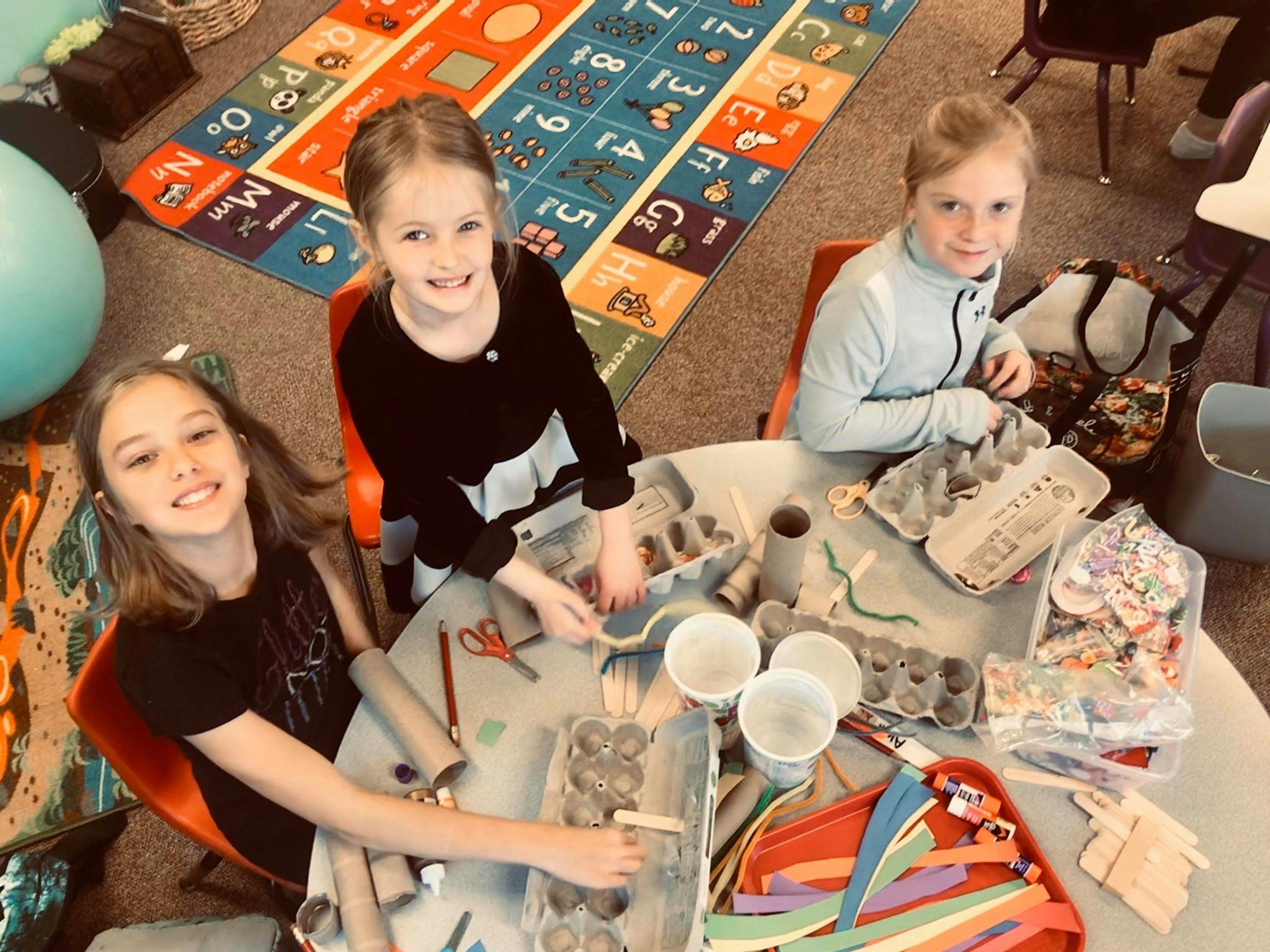 Three children at a table with craft supplies