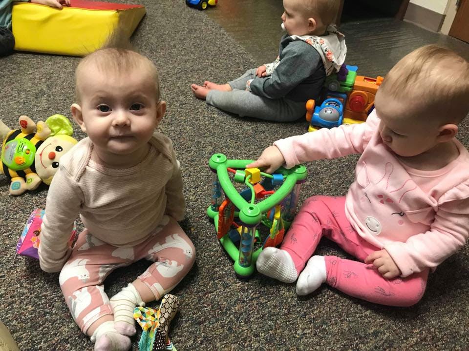 Three babies playing with toys on a carpeted floor